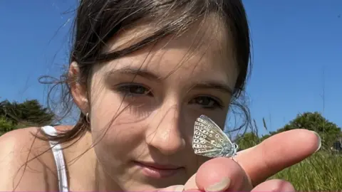 Butterfly Conservation Girl holds a butterfly on her finger as part of a survey