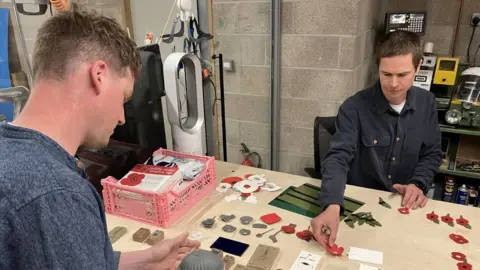 Two men arranging poppies on a desk