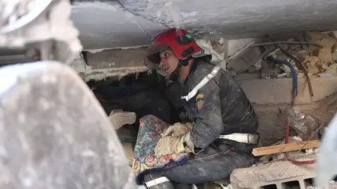 Getty Images Rescuer trying to help people under the rubble