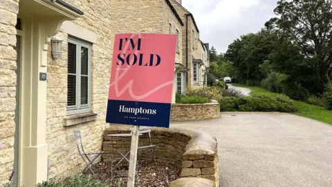 BBC A 'sold' sign outside a traditional stone Cotswold property