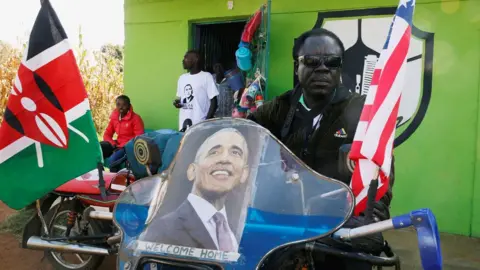 Reuters A Kenyan man sitting on a motorbike decorated with a poster of Barack Obama and the Kenyan and US flags, Kogelo, Kenya - Monday 16 July 2018