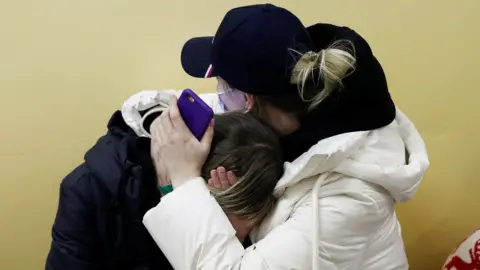 Reuters People from Ukraine comfort each other at a refugee shelter