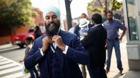 Reuters New Democratic Party leadership candidate Singh puts on his tie at a meet and greet event in Hamilton