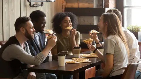 Getty Images Group of people eating pizza