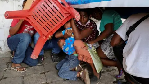 Reuters Migrants use a chair to protect themselves from rocks during a protest by migrants to demand speedy processing of humanitarian visas to continue on their way to the United States, outside the office of the National Migration Institute (INM) in Tapachula, Mexico February 22, 2022.