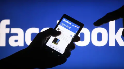 Reuters Hands holding a mobile phone with Facebook displayed