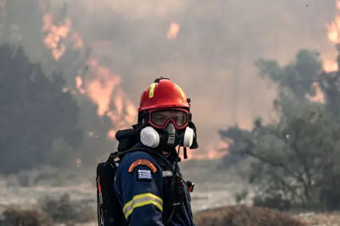 Spyros Bakalis / AFP A firefighter looks on during a fire near the village of Vati, Rhodes