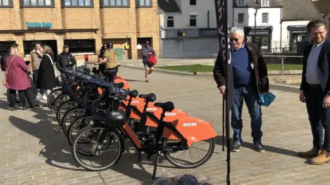 John Devine/BBC People in Cathedral Square, Peterborough, looking at a number of e-bikes