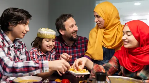 Jasmin Merdan / Getty Images A Muslim family gathered around food during Ramadan