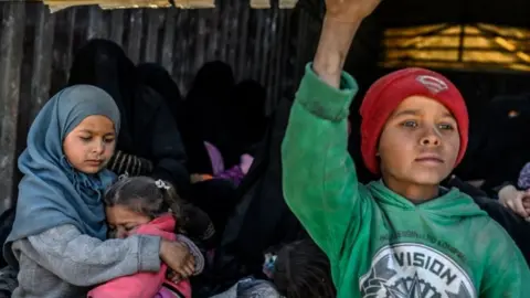 AFP Children and women sit in the back of a lorry waiting to be evacuated