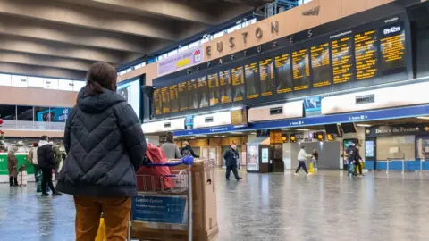 Getty Images Passengers at Euston Station wait to find out if their trains are running on time as they prepare to leave the capital on December 19, 2020 in London