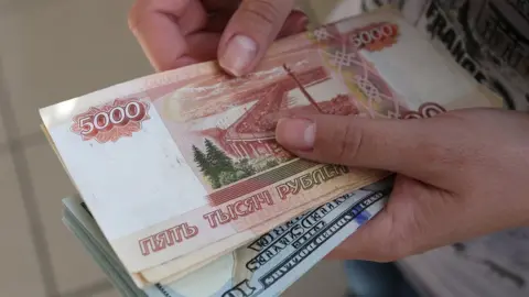 Getty Images An employee holds 5000 ruble banknotes inside a foreign currency exchange bureau in Russia.