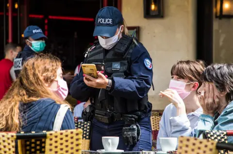 EPA French police officers control customers' health passes at a bar in Paris