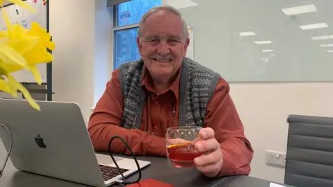 BBC/Jess Warren Professor David Nutt holding a glass of red liquid