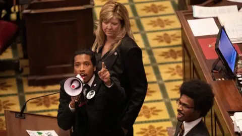 Reuters Tennessee State Representative Justin Jones, standing with Rep. Justin Pearson and Rep. Gloria Johnson, calls on his colleagues to pass gun control legislation from the well of the House Chambers during the legislative session, three days after the mass shooting at The Covenant School, at the State Capitol in Nashville, Tennessee, U.S. March 30, 2023.