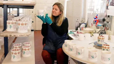 PA Media Rachel Matthews, a sponge decorator at Emma Bridgewater pottery in Stoke-on-Trent, Staffordshire, paints a commemorative mug following the death of Queen Elizabeth II. P