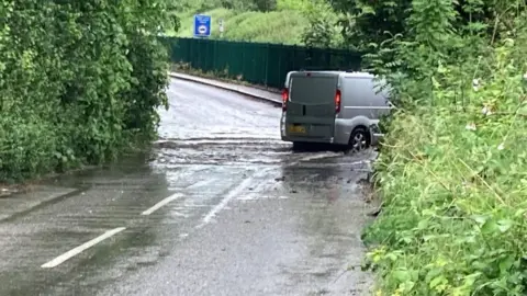 Luke Deal/BBC A van driving through flood water in Needham Market