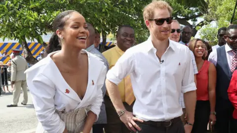 Getty Images Rihanna laughs, standing next to Prince Harry at awareness event in Barbados