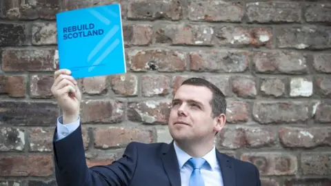Jane Barlow/PA Douglas Ross raises up the Scottish Conservative manifesto
