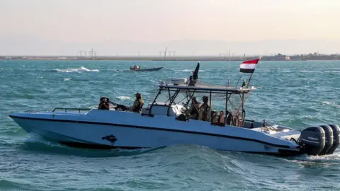 Getty Images Yemeni coastguard members loyal to the internationally-recognised government ride in a patrol boat in the Red Sea off of the government-held town of Mokha in the western Taiz province, close to the strategic Bab al-Mandab Strait, on December 12, 2023.