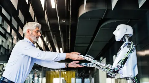 Getty Images A man and a robot holding hands