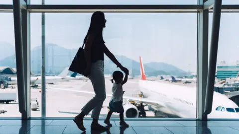 Getty Images A silhouette of a woman and a child walking past a plane