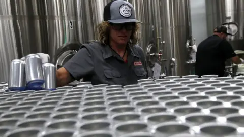 Getty Images Kathryn Fisher with Can Van, a mobile canning company, places empty aluminum cans on a conveyor belt to be filled with beer at Devil's Canyon Brewery on June 6, 2018 i