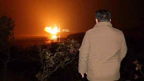 Reuters Kim Jong Un looks on as a rocket is launched in the distance