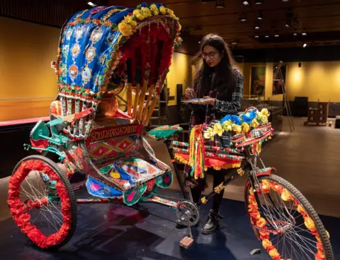 Getty Images Artist Daya Bhatti puts the finishing touches to a decorated rickshaw artwork