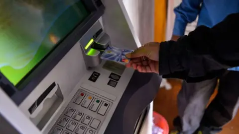 Getty Images An Indian man inserts his card to withdraw money from a mobile bank ATM machine in New Delhi on November 15, 2016.