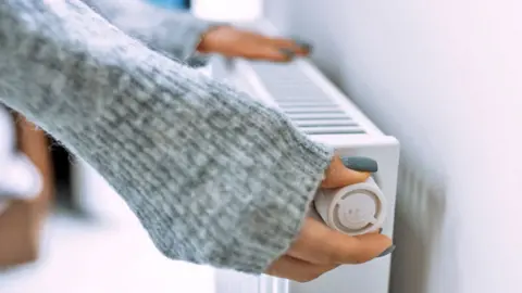 Getty Images A woman adjusts a radiator