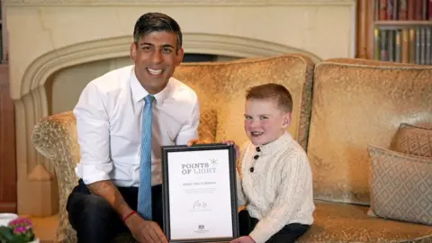 PA Media Rishi Sunak presents Dáithí Mac Gabhann with the Points of Light award