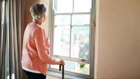 Getty Images Older woman looking out of the window