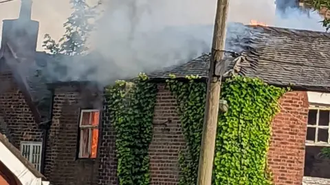 Anton Thorley Smoke rises from Ford Green House, with flames behind a top-floor window