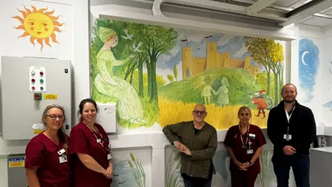 West Suffolk Hospital West Suffolk Hospital staff members and James Mayhew in front of the mural