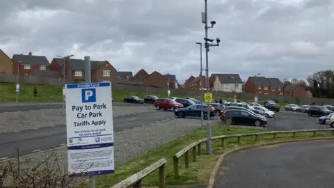  Martin Heath/BBC Car park in front of a modern housing development