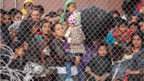 Getty Images Migrants are gathered inside the fence of a makeshift detention center in El Paso, Texas on Wed. March 27, 2019