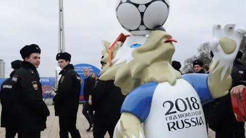 Reuters Police officers walk past the official mascot for the 2018 FIFA World Cup Russia, Zabivaka during the opening of the Football Park in Rostov-on-Don, Russia March 31, 2018