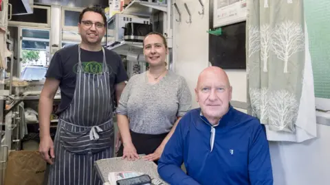 Historic England Cristiano and Terresa Sanchez who run the Pont Street shelter, and Jimmy Jenkins, a cab driver of 48 years who is the trustee of the Cabmen's Shelter Fund