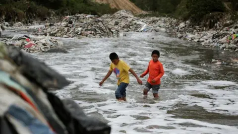 Reuters Two boys cross the polluted waters of the Las Vacas river