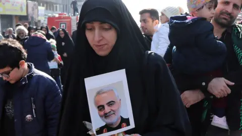 EPA An Iranian woman holds a picture of Iranian Revolutionary Guards Corps Lieutenant General Qasem Soleimani during a funeral ceremony in Tehran, 6 January 2020