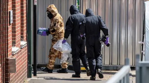 Getty Images People in hazmat suits enter a property in Amesbury in Wiltshire after Novichok was found there