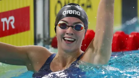 Getty Images Emily in the pool smiling with her hand up