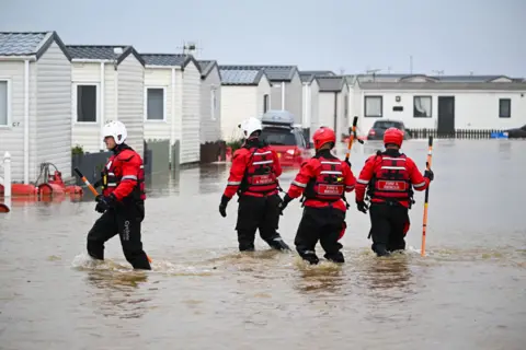 Getty Images Fire and rescue officers search for people in need of rescue from their holiday chalets at Freshwater Beach Holiday Park, on November 02, 2023 in Burton Bradstock, Dorset.