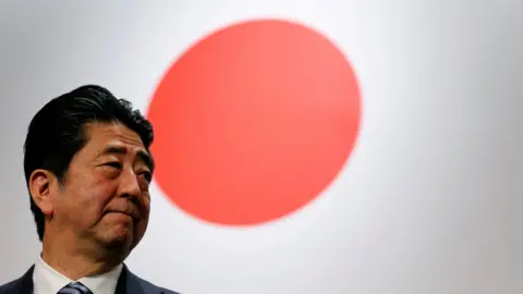 Reuters Japan's Prime Minister Shinzo Abe stands in front of Japan's national flag