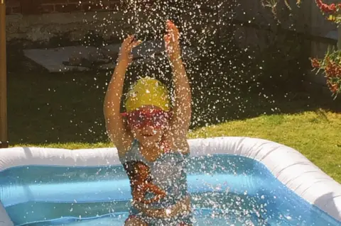 Sam B Young girl splasshing in a paddling pool