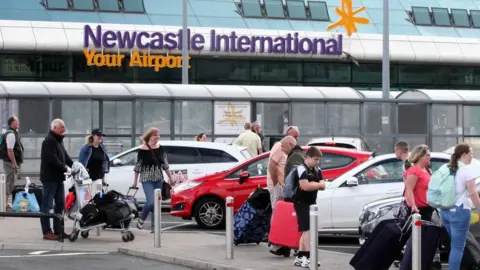 BBC Newcastle Airport with travellers in the foreground