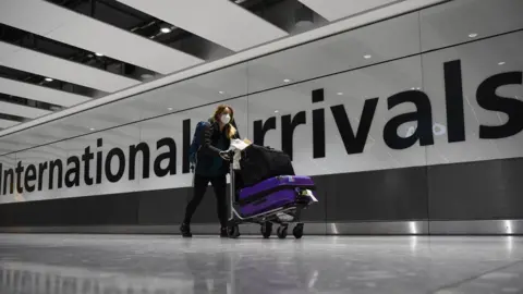 PA Media A passenger pushes luggage through the Arrival Hall of Terminal 5 at London"s Heathrow Airport