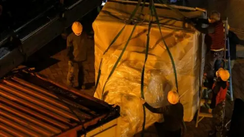 Pillar of Shame statue being loaded into a truck