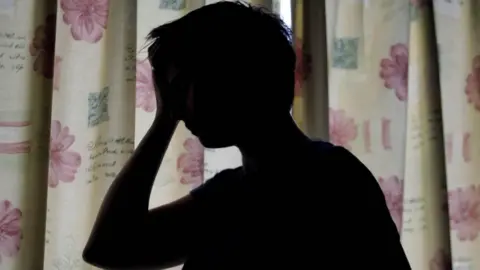 PA Media Silhouette of a woman with head in her hand